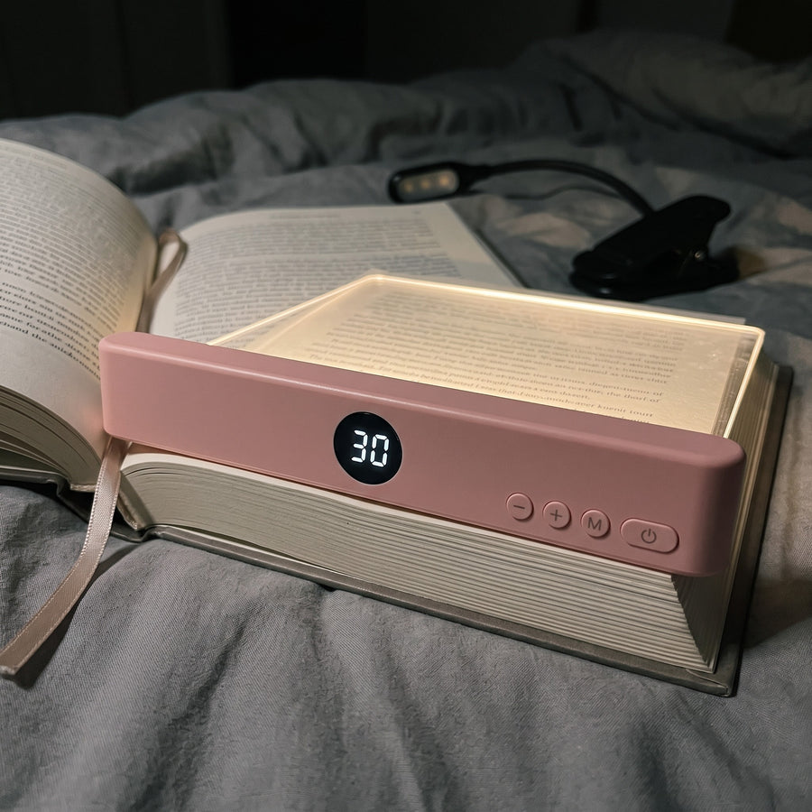 The reading light resting on a hardcover page, with a clip-on book light switched off beside it