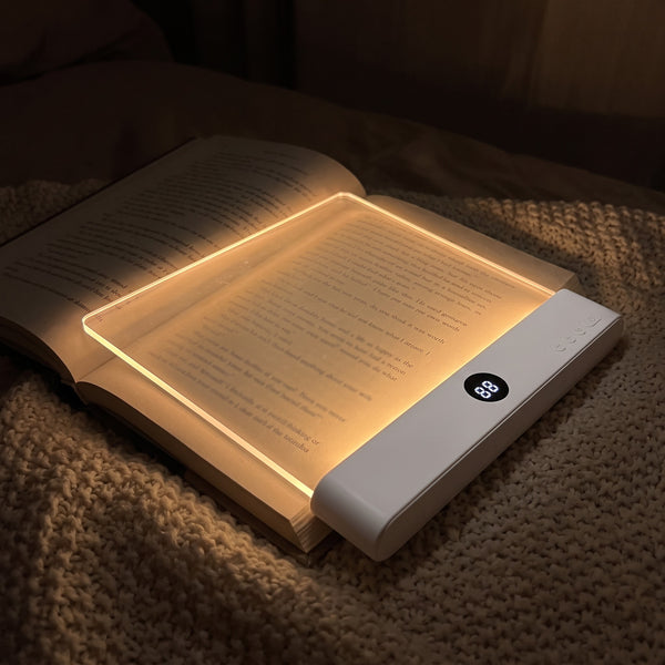 The reading light glowing warm on a book page while the room stays dark